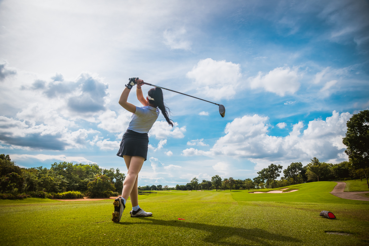 Professional woman golfer teeing golf in golf tournament competition at golf course for winner.